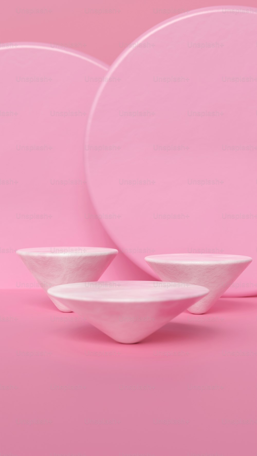 a set of three white plates on a pink background