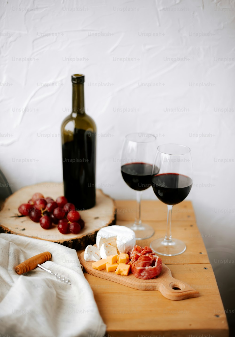 a wooden table topped with two glasses of wine and cheese