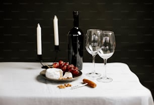 a plate of cheese and grapes next to a bottle of wine