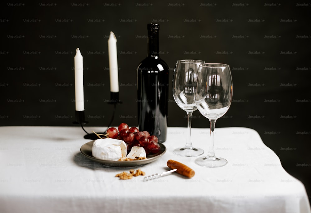 un piatto di formaggio e uva accanto a una bottiglia di vino