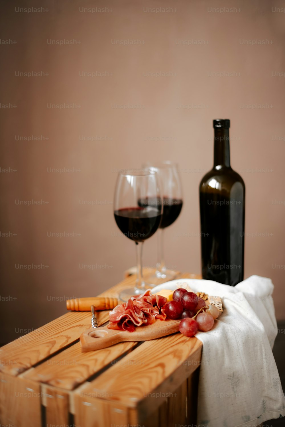 un tavolo di legno sormontato da una bottiglia di vino e un bicchiere di vino