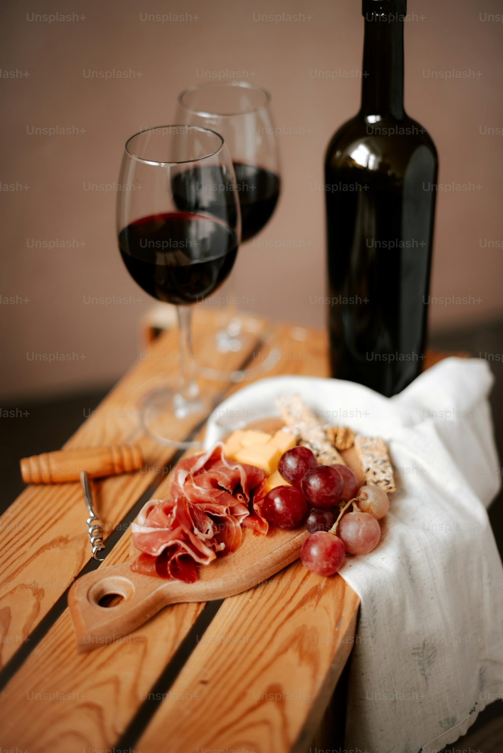 a wooden table topped with a bottle of wine and a plate of food