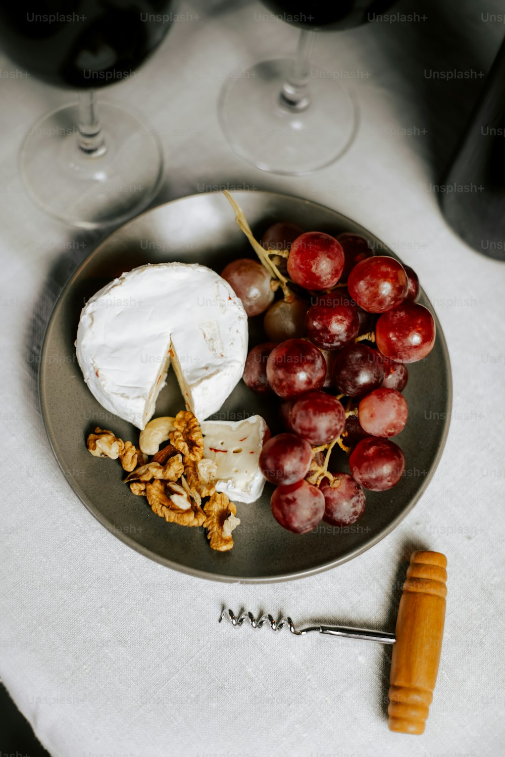 a plate of cheese, grapes, walnuts, and crackers