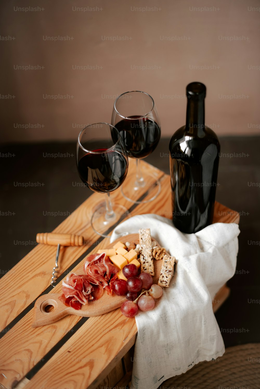 a wooden table topped with a plate of food and two glasses of wine