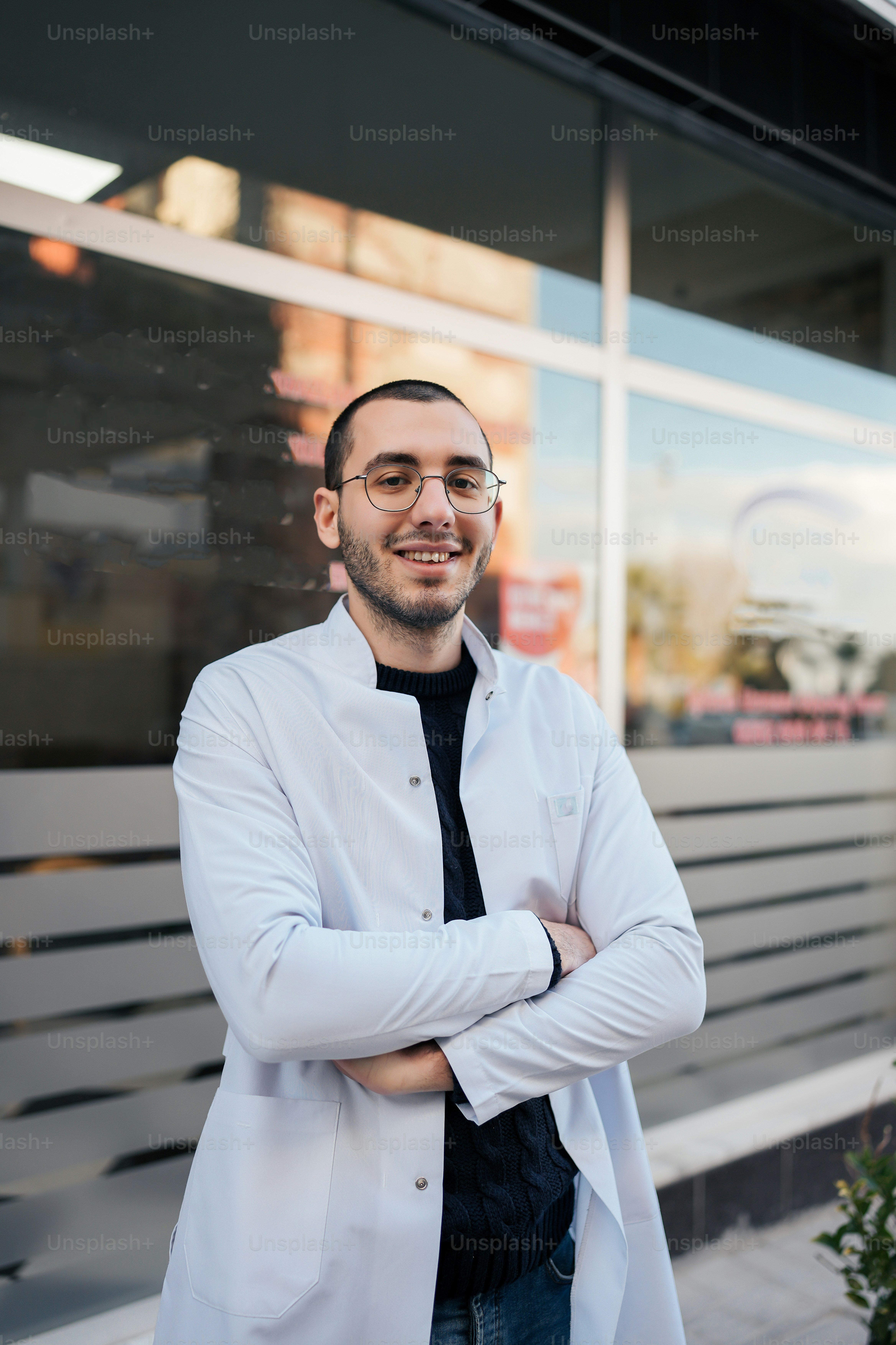 Un hombre con bata blanca y corbata parado frente a un edificio