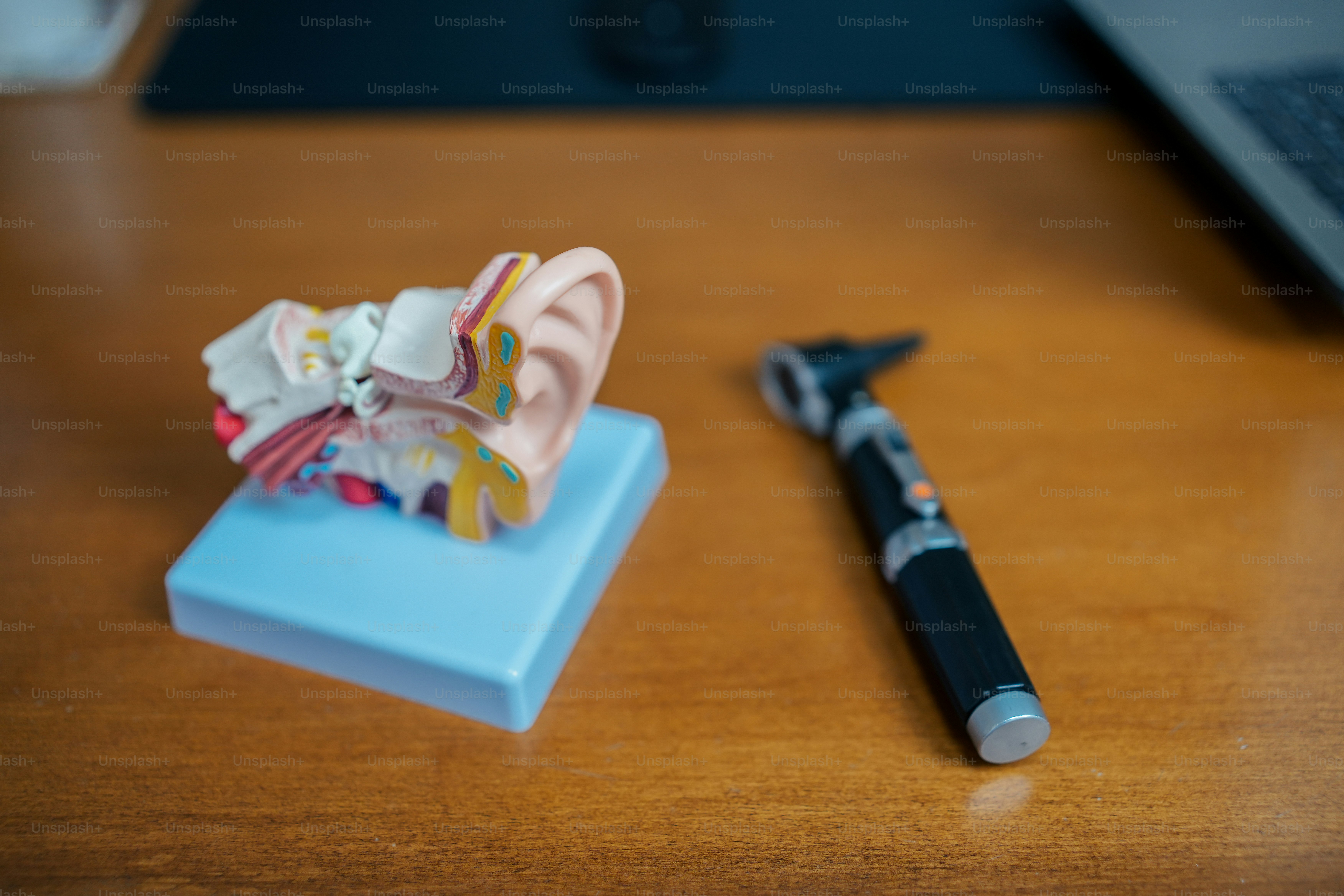a desk with a pen, earring holder, and a laptop