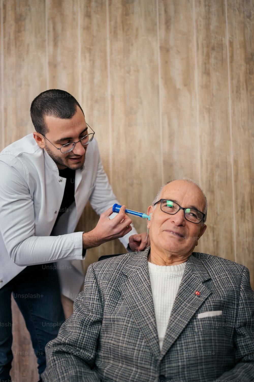 a man getting his teeth brushed by a man in a suit