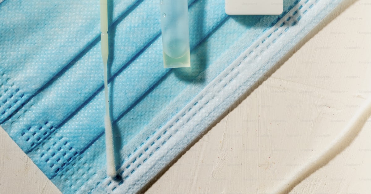 A medical mask and a tube of toothpaste on a table photo – Covid ...
