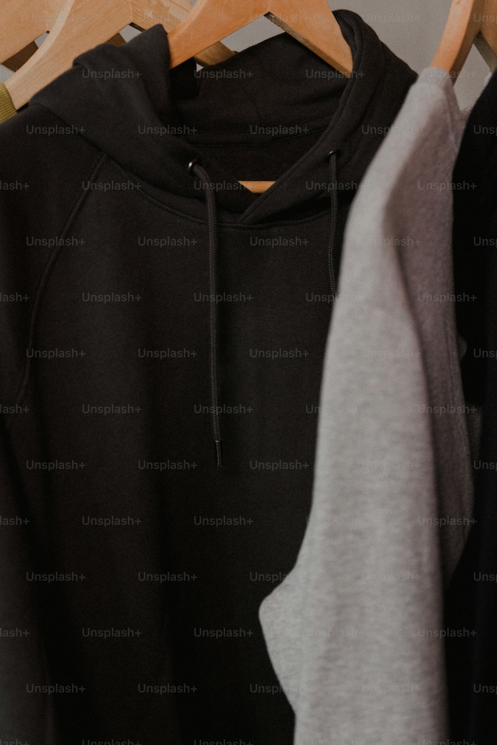 a black and grey hoodie hanging on a wooden hanger