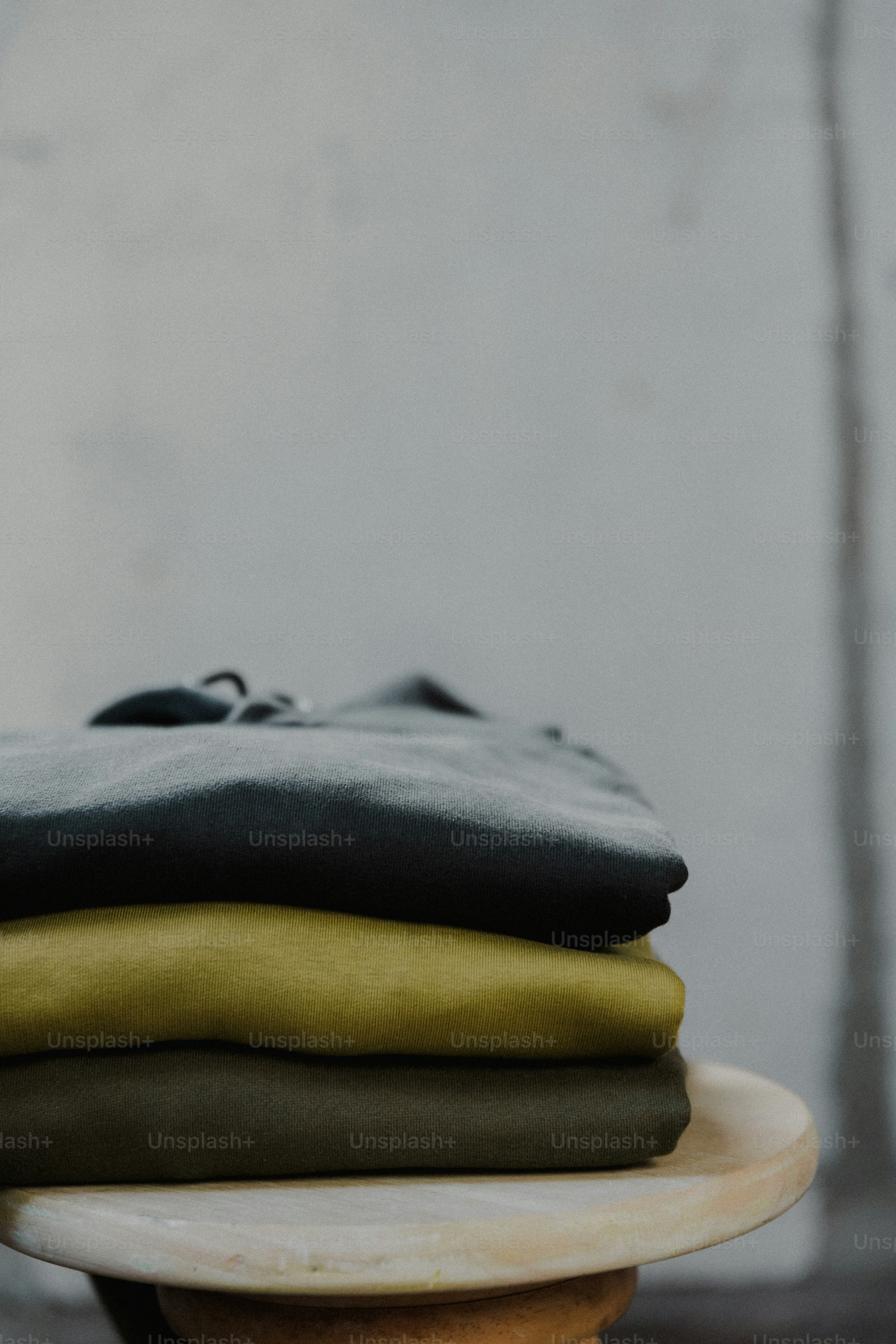 a stack of folded clothes sitting on top of a wooden table