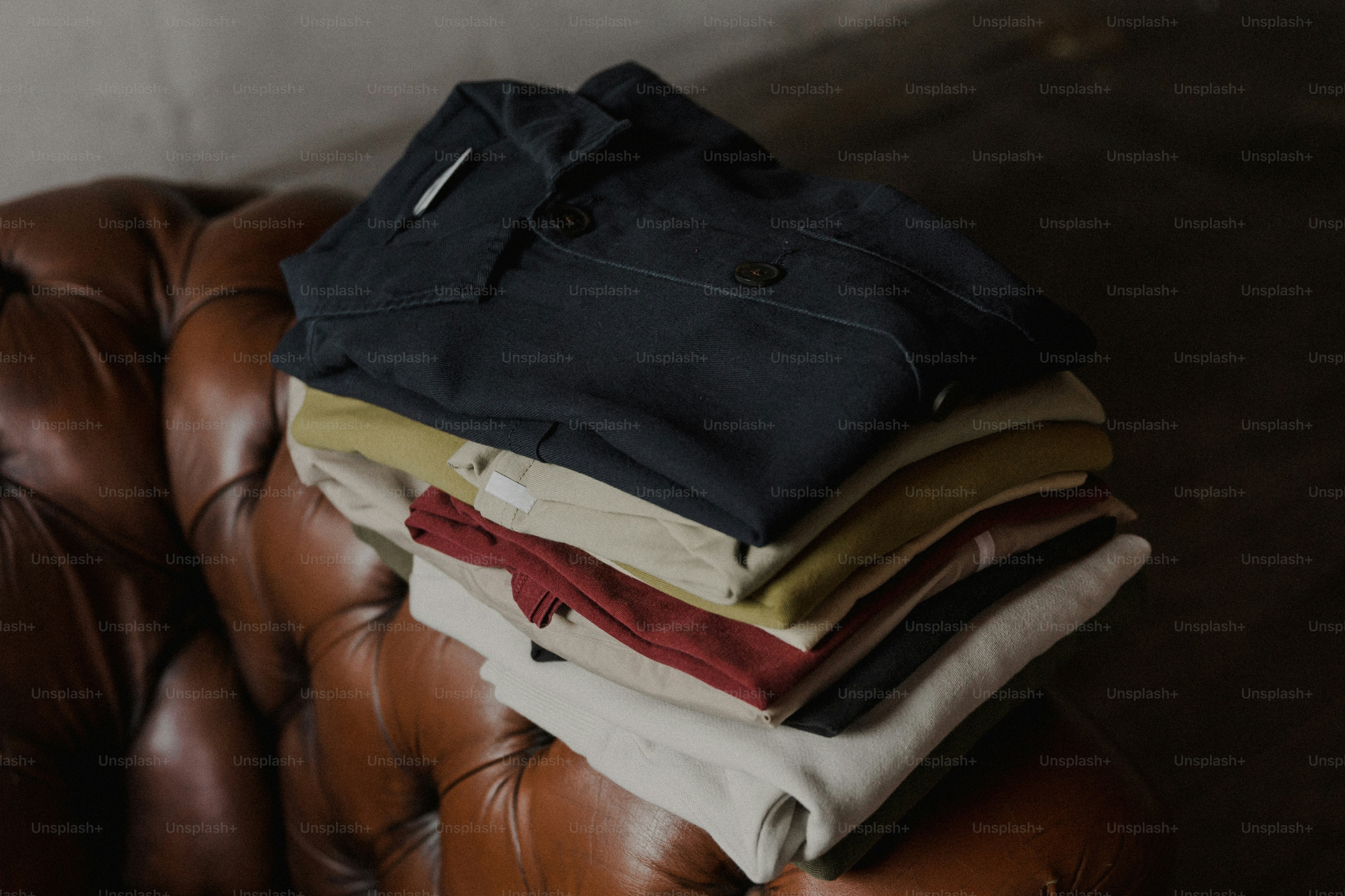a pile of clothes sitting on top of a brown leather chair
