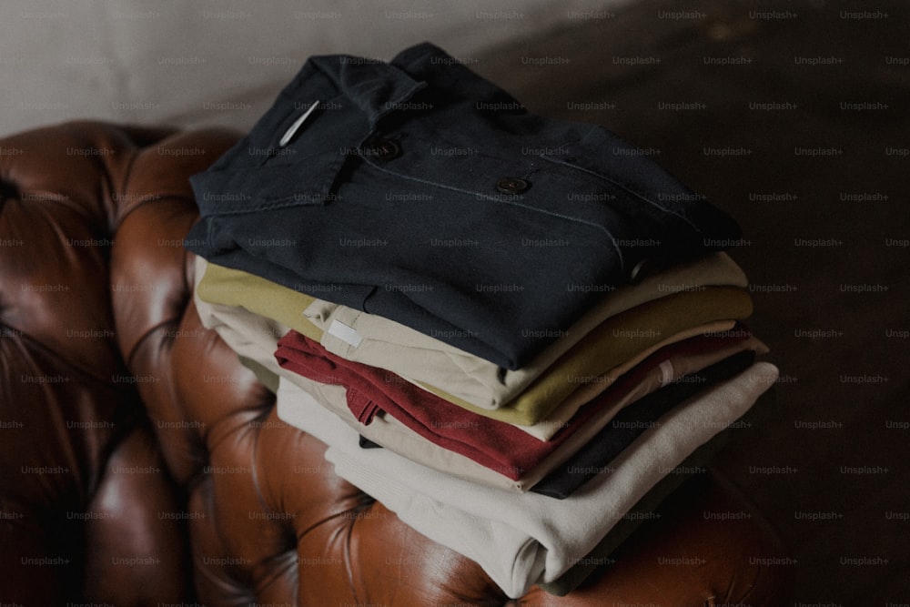 a pile of clothes sitting on top of a brown leather chair