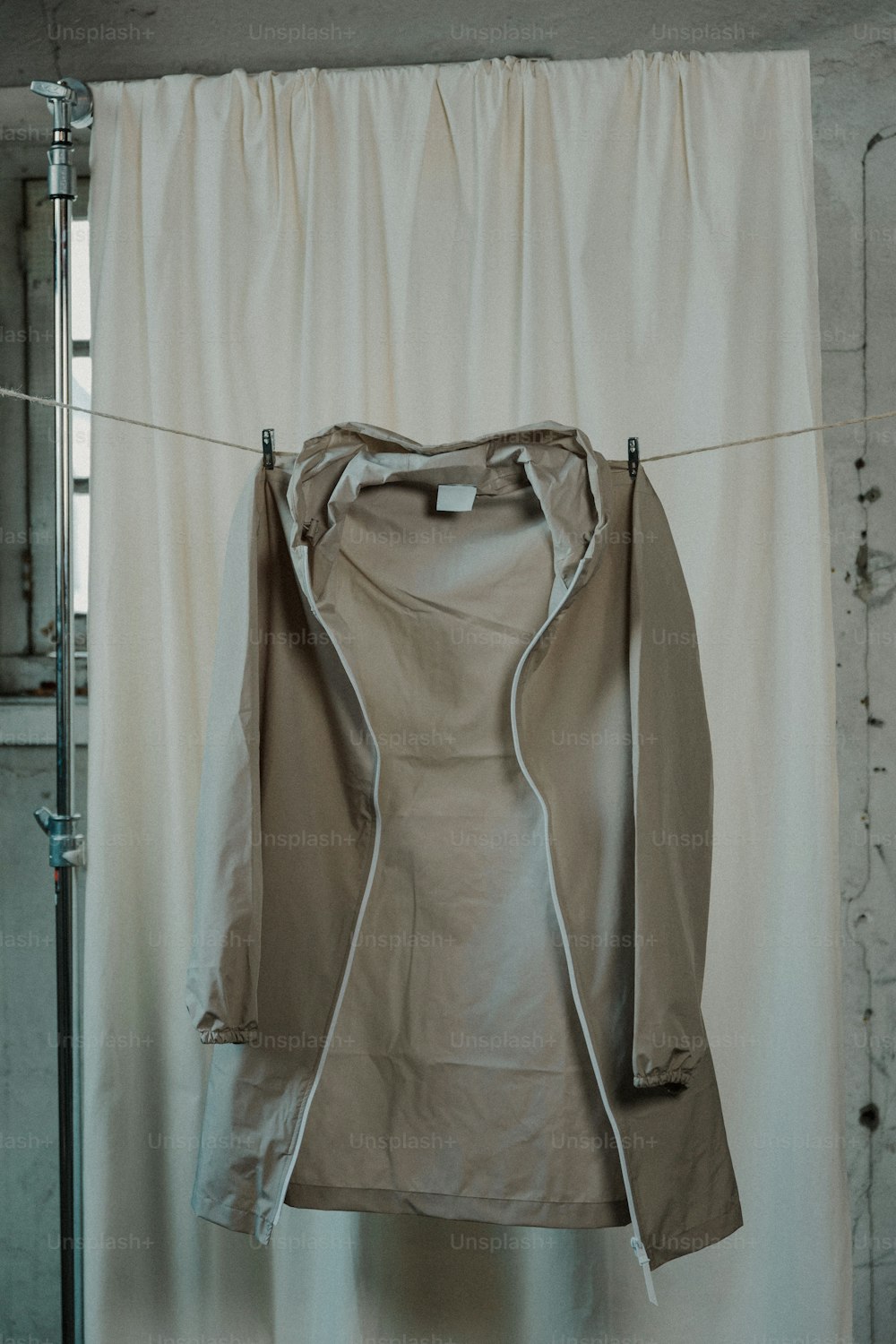 une veste accrochée à une corde à linge devant un rideau