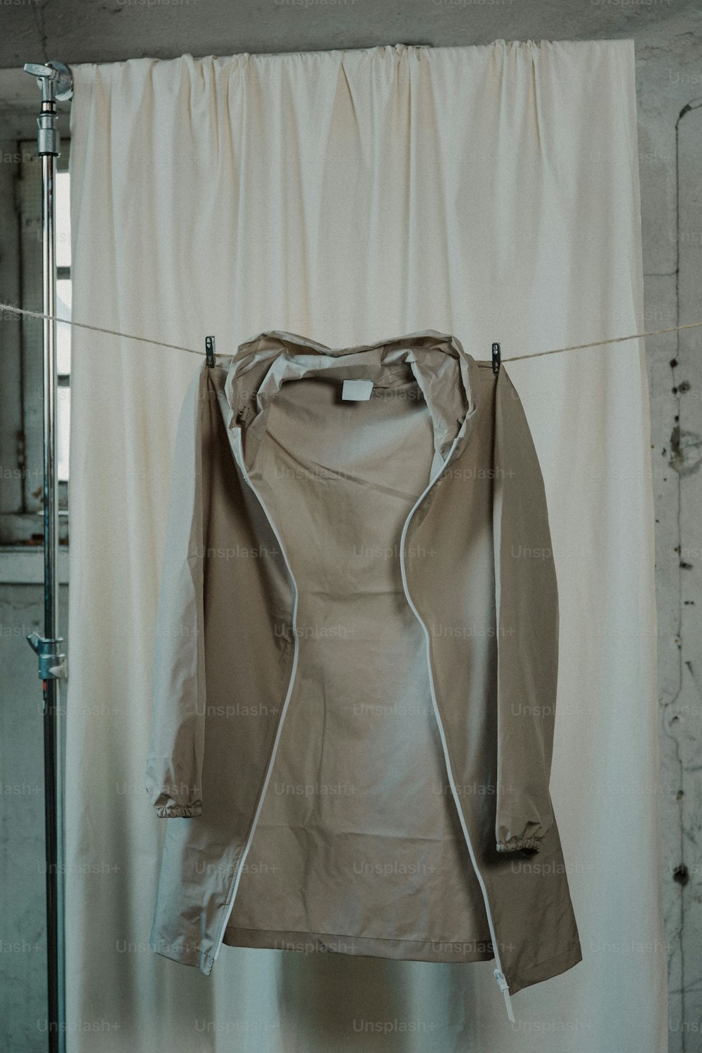 a jacket hanging on a clothes line in front of a curtain