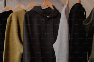 a row of different colored sweatshirts hanging on a rack