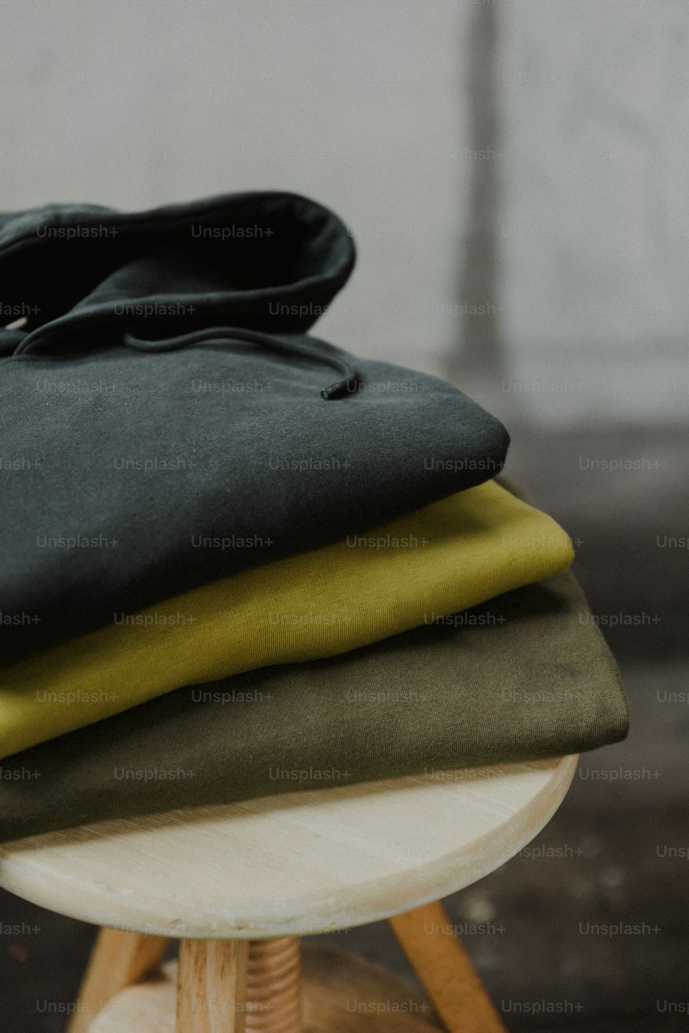 a stack of folded clothing sitting on top of a wooden stool