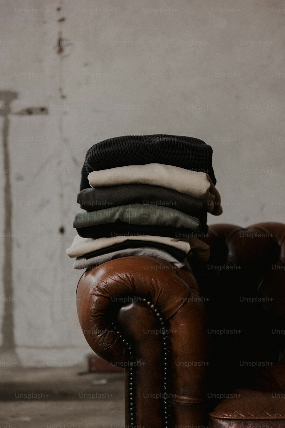 a pile of clothes sitting on top of a brown leather chair