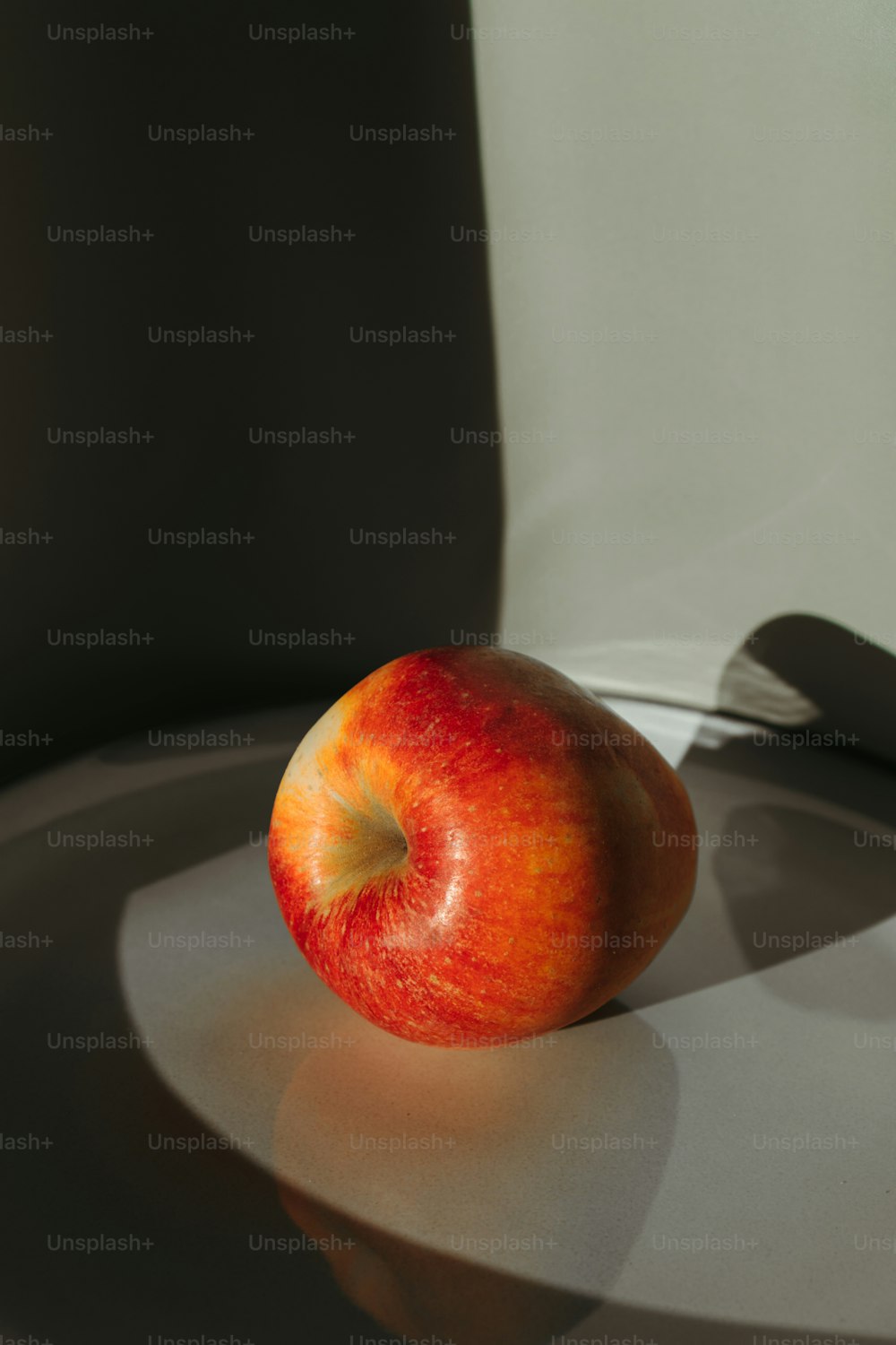 a red apple sitting on top of a white plate