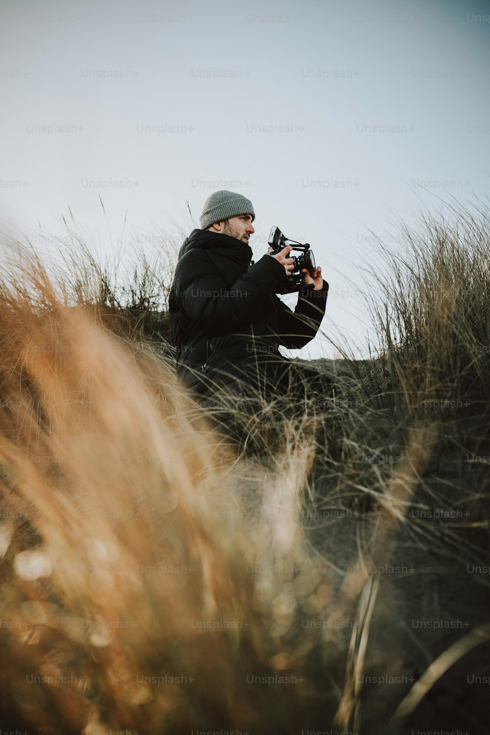 um homem sentado em um campo tirando uma foto com uma câmera