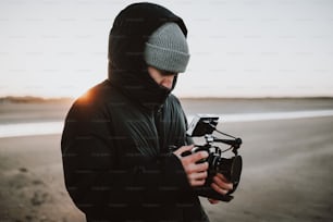 um homem em pé em uma praia segurando uma câmera