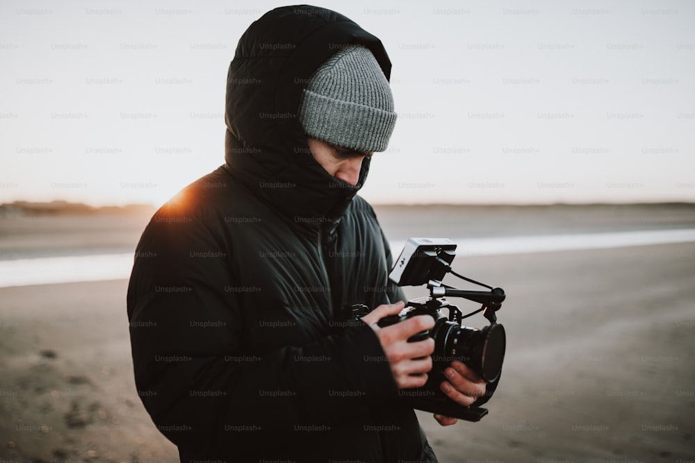 Un uomo in piedi su una spiaggia con in mano una macchina fotografica