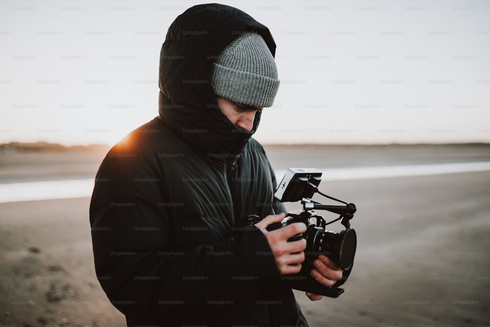 a man standing on a beach holding a camera