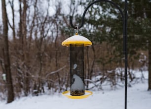 a bird feeder hanging from a pole in the snow