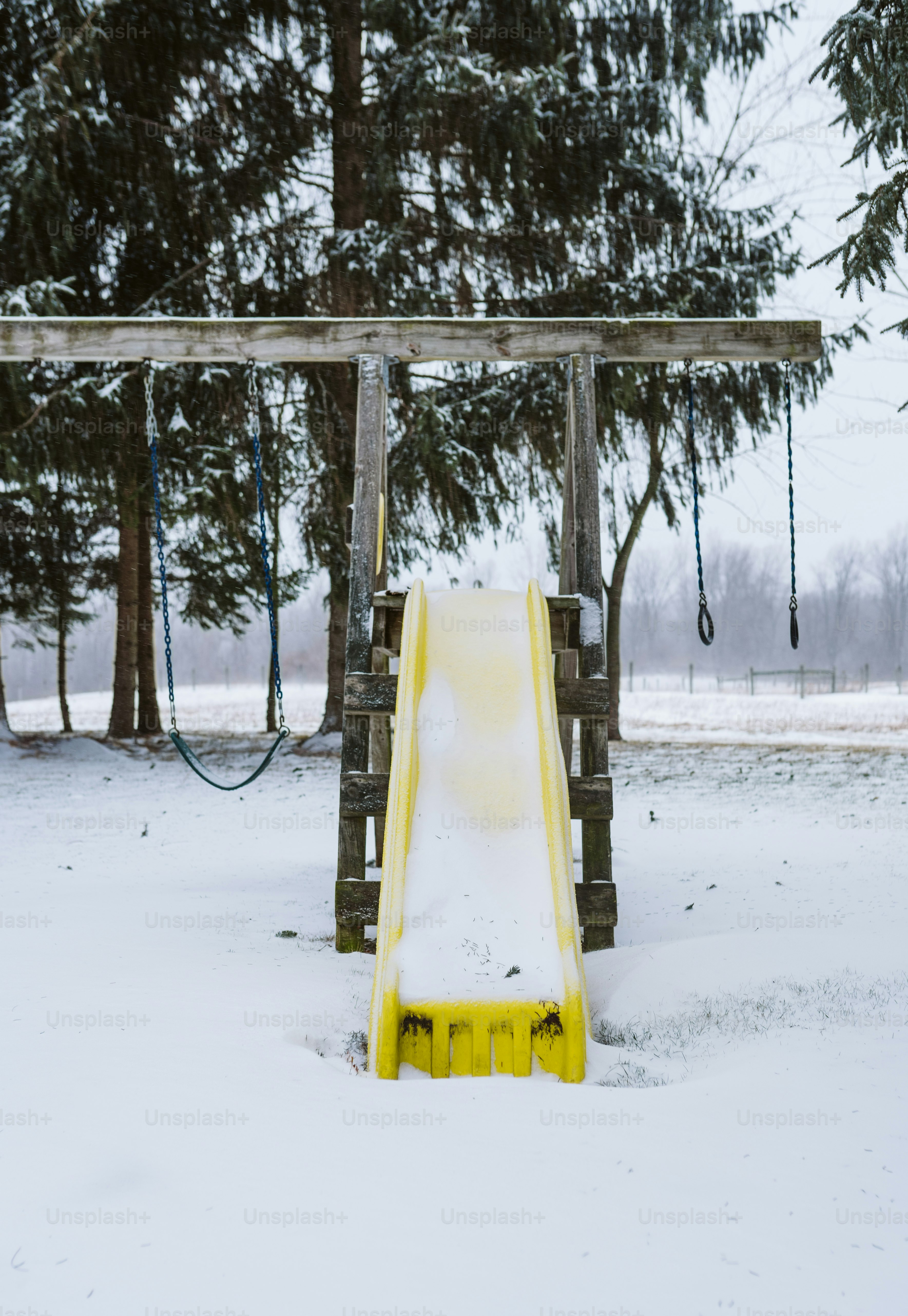 A yellow slide sitting in the middle of a snow covered field photo ...