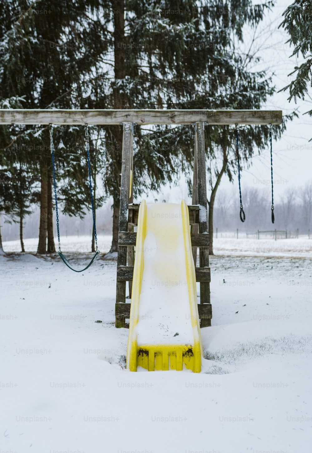 a yellow slide sitting in the middle of a snow covered field
