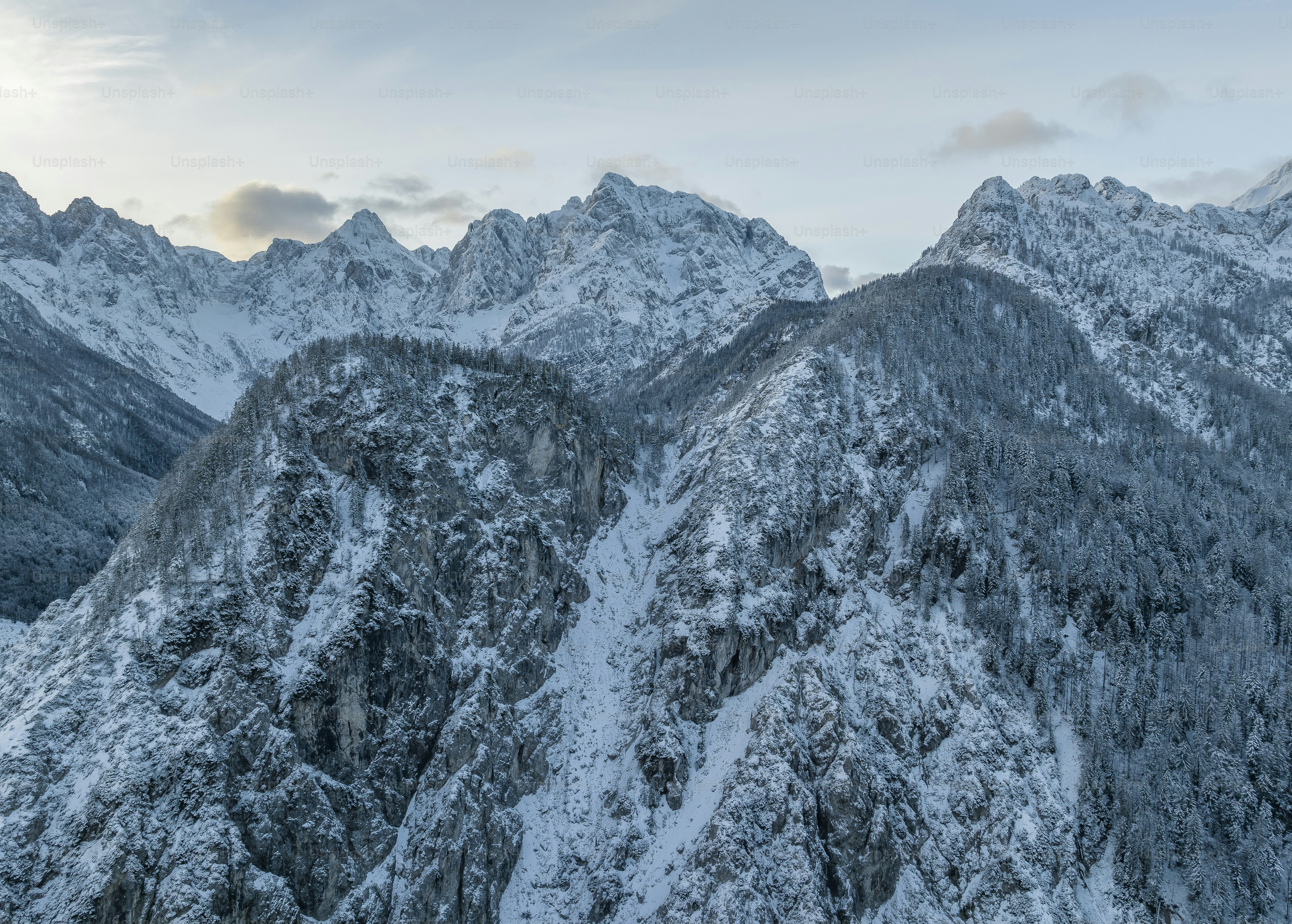 Une chaîne de montagnes couverte de neige sous un ciel nuageux