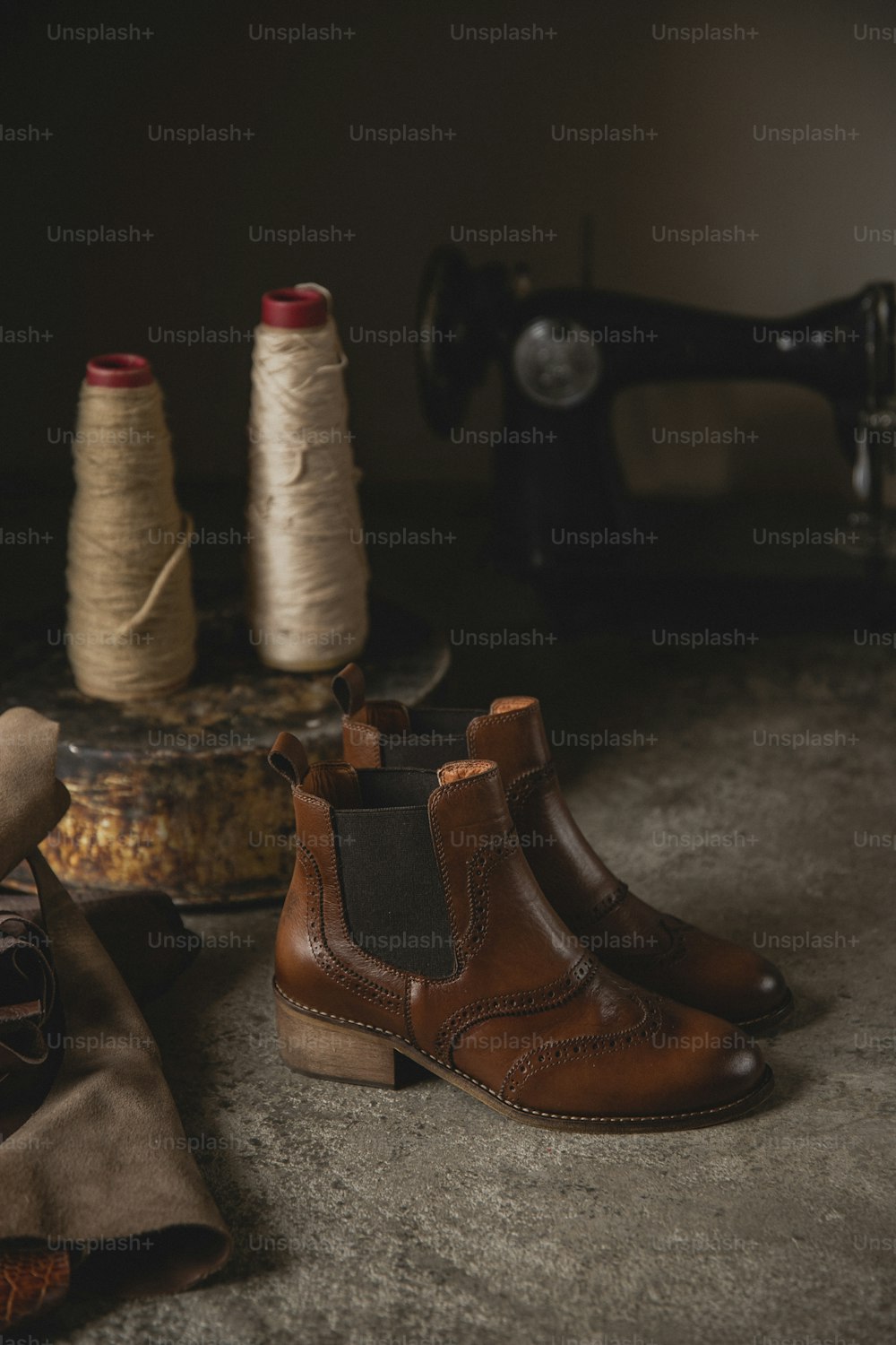 a pair of brown boots sitting next to a spool of thread