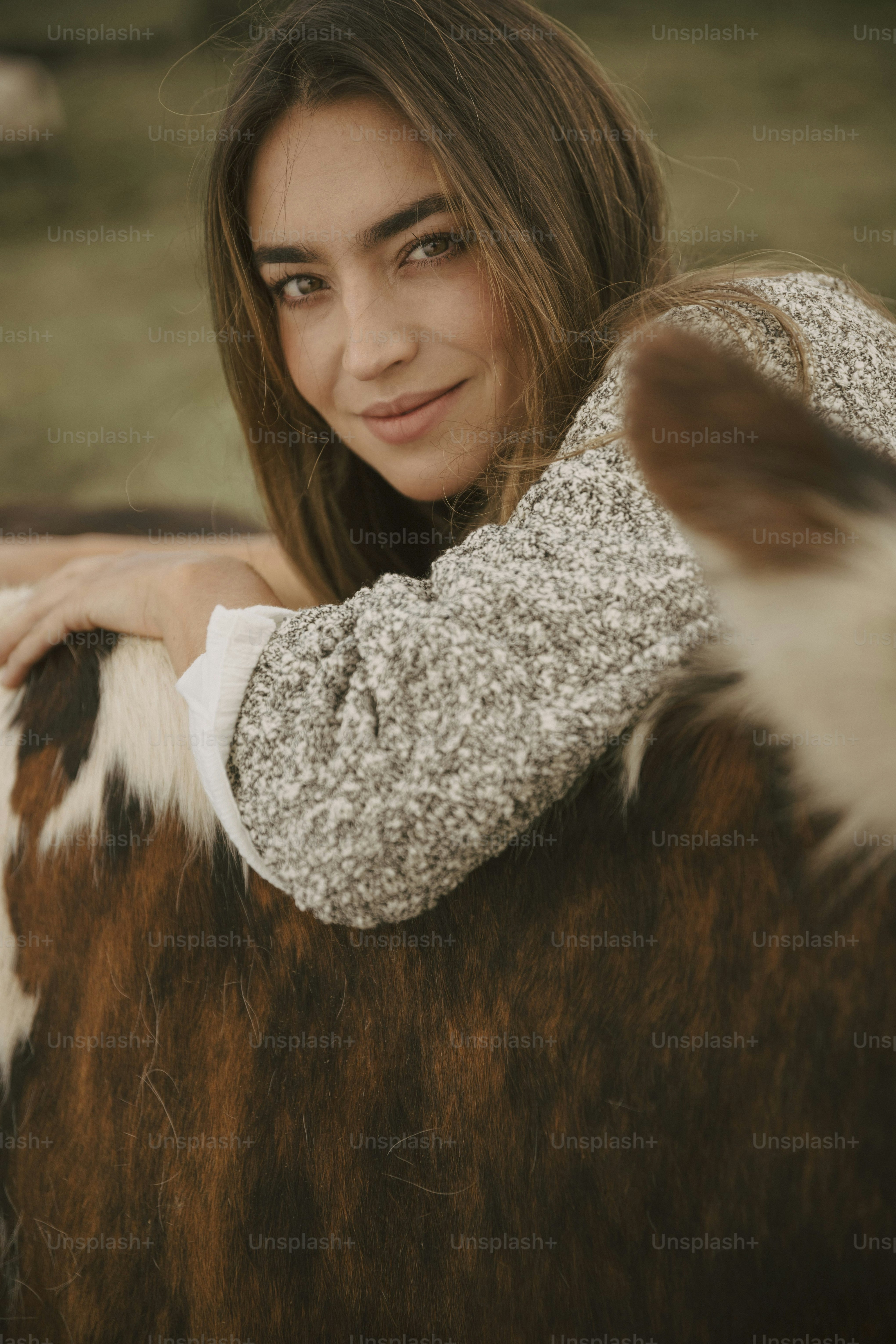 Una hermosa joven de pie junto a un caballo marrón y blanco