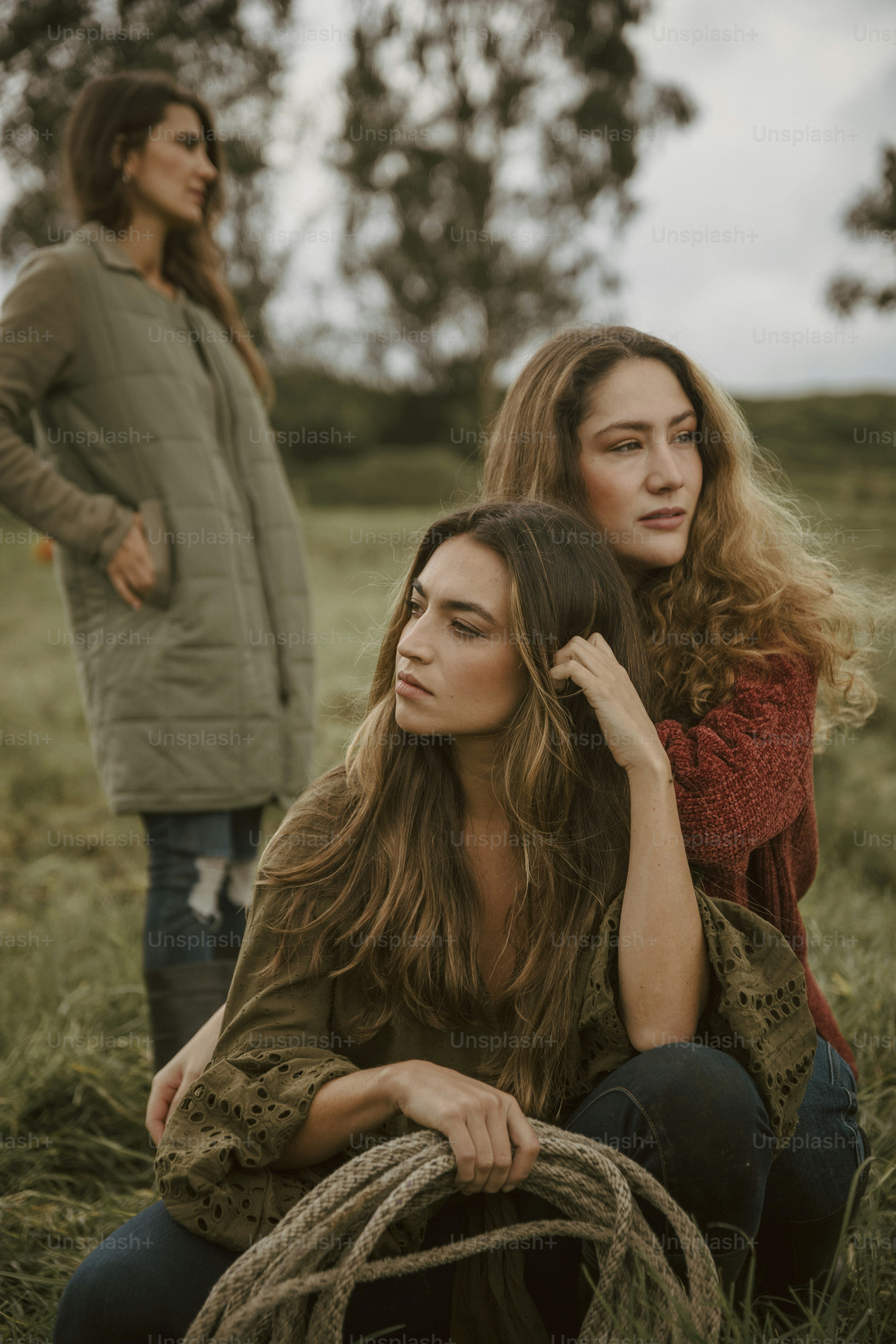 two women sitting in a field with a rope