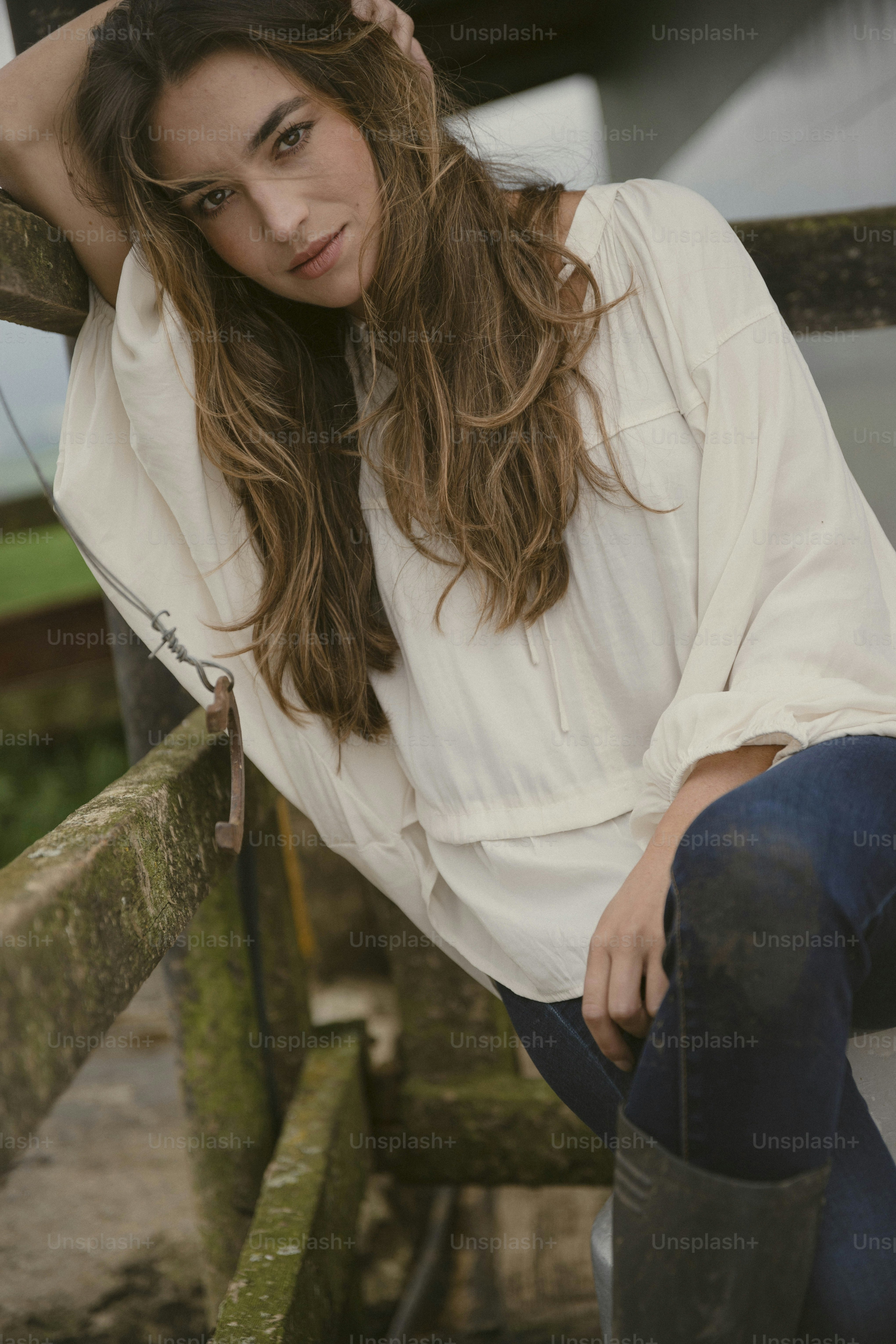a woman with long hair sitting on a fence