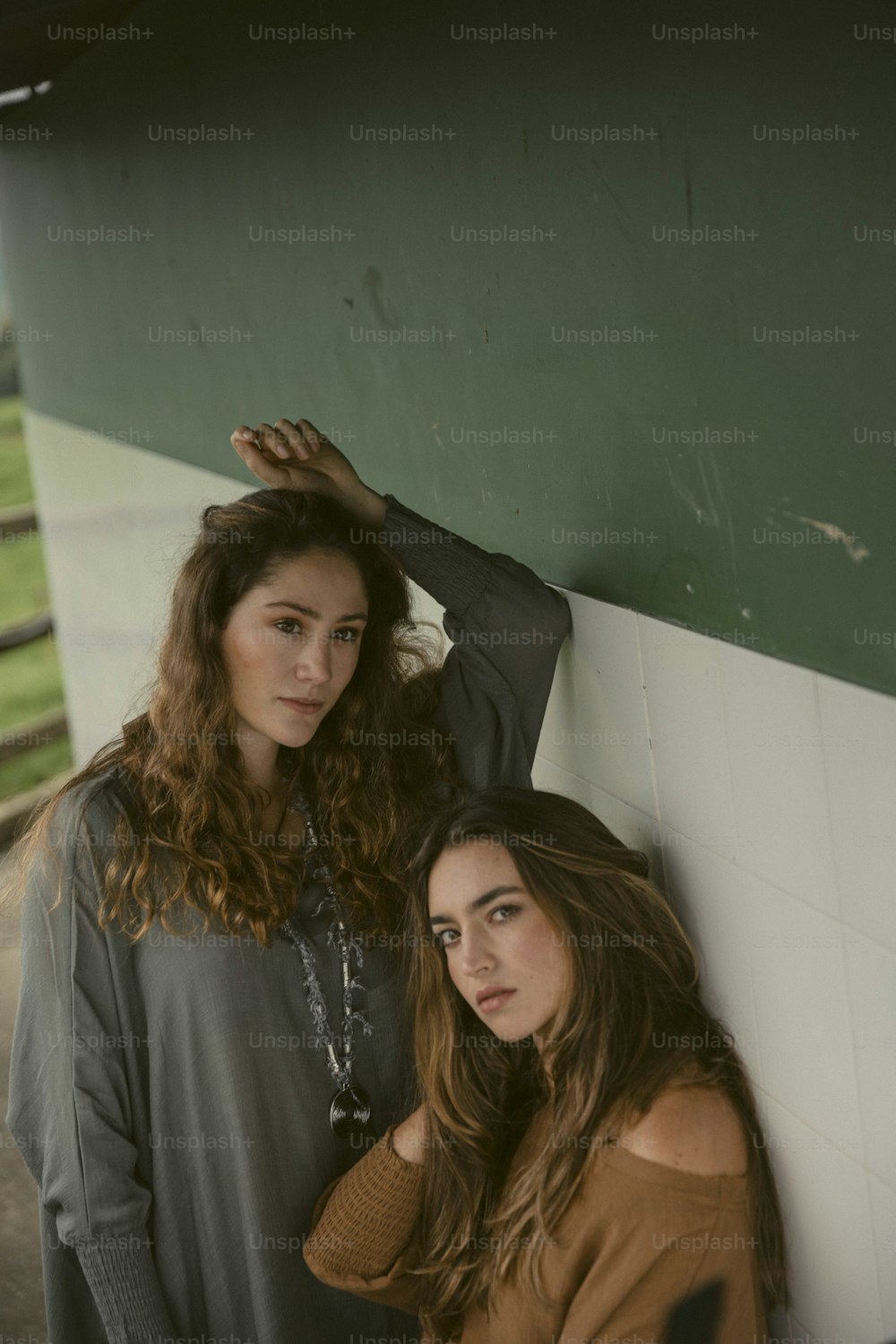 two women standing next to each other near a wall