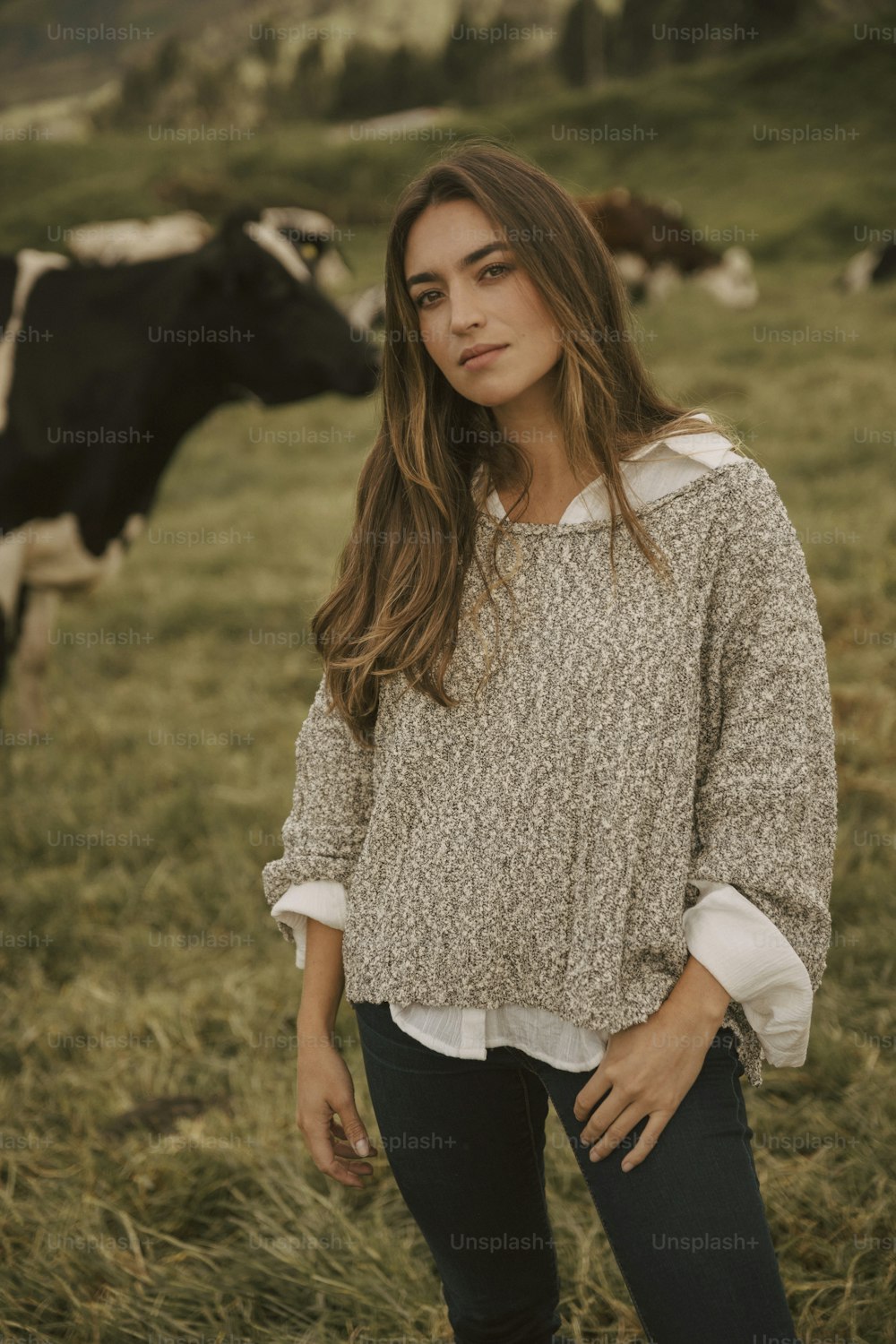 uma mulher em pé na frente de um rebanho de vacas