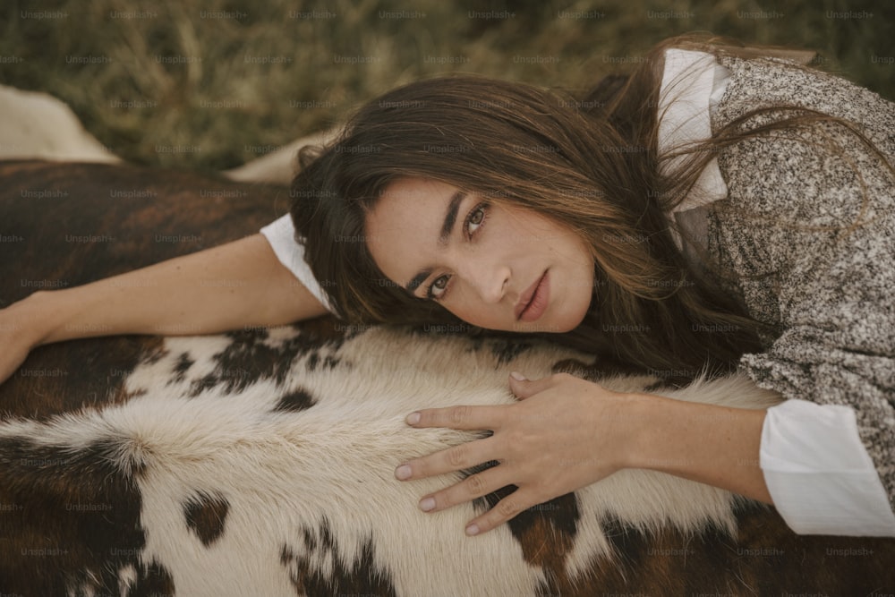 uma mulher deitada em cima de uma vaca marrom e branca