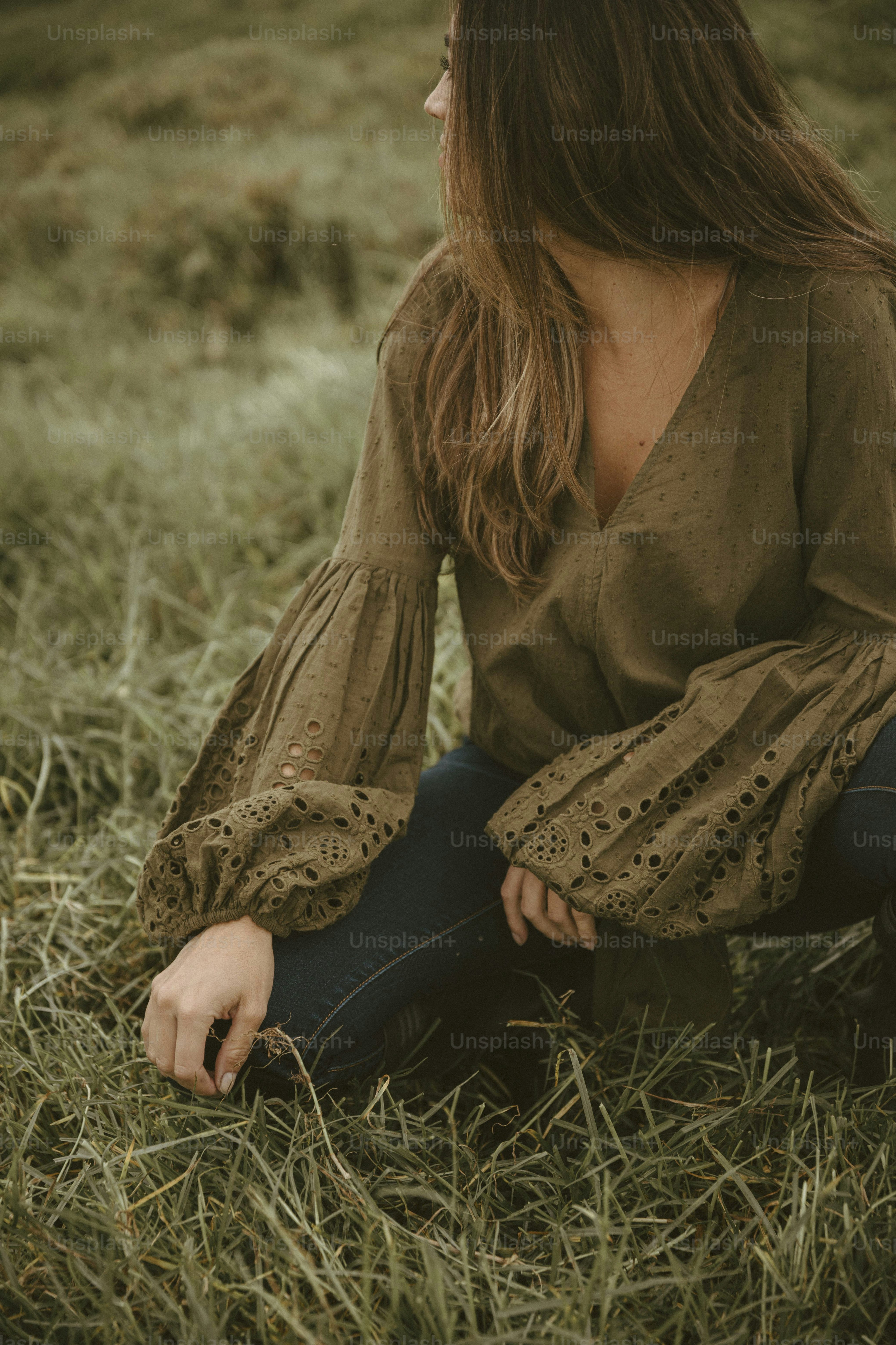 a woman sitting in the grass with her eyes closed