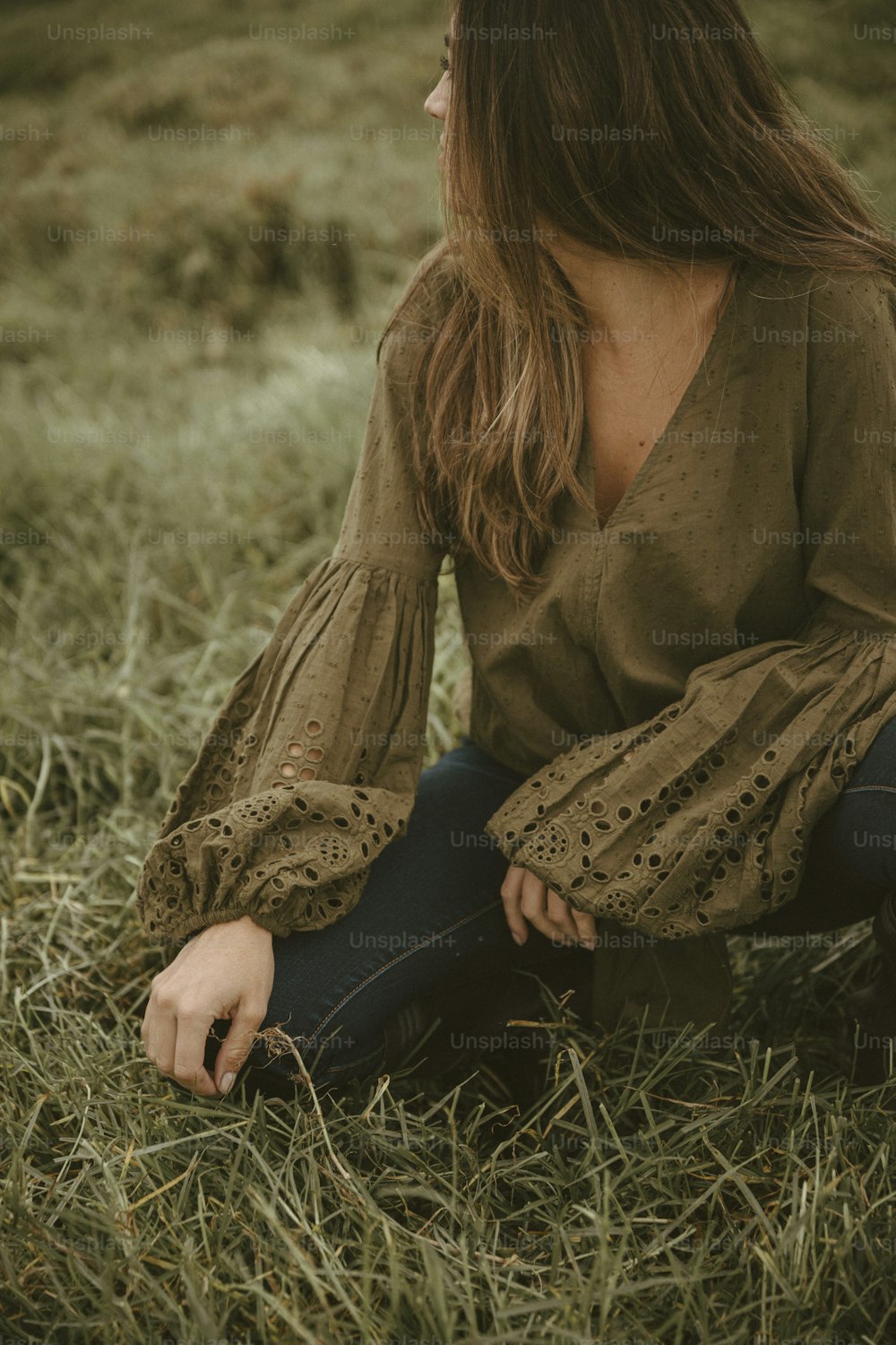 uma mulher sentada na grama com os olhos fechados