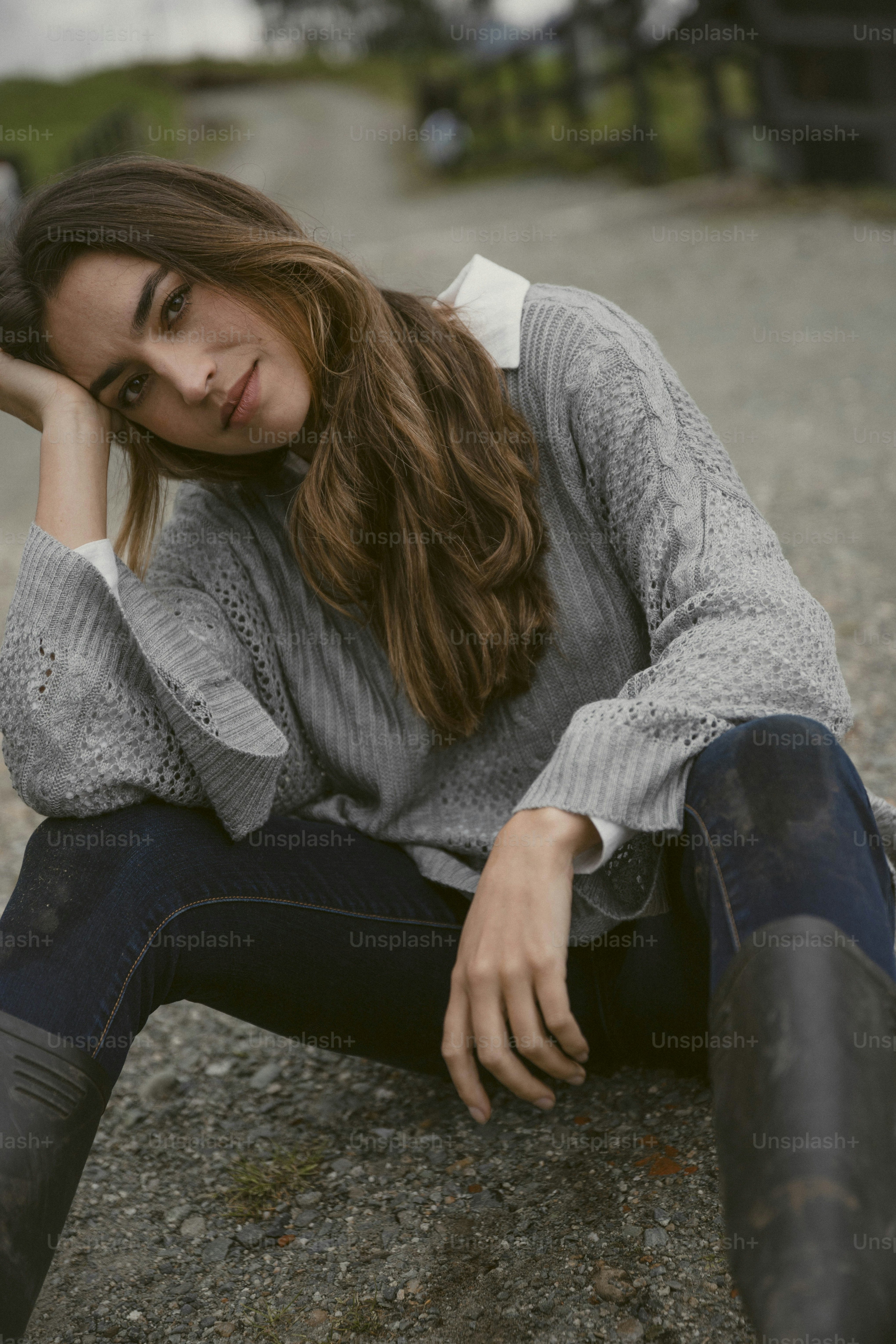 a woman sitting on the ground with her hand on her head