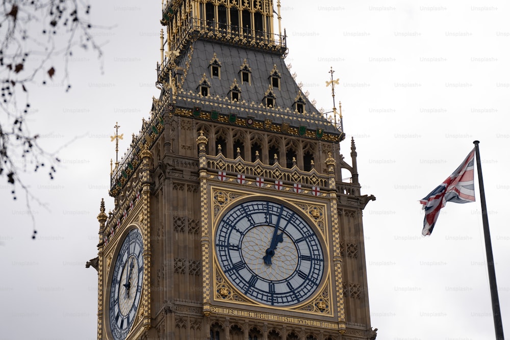 Una torre del reloj con una bandera británica ondeando en el fondo