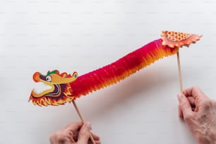 a hand holding a red and yellow dragon puppet