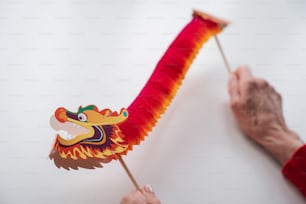 a hand holding a red and yellow dragon kite