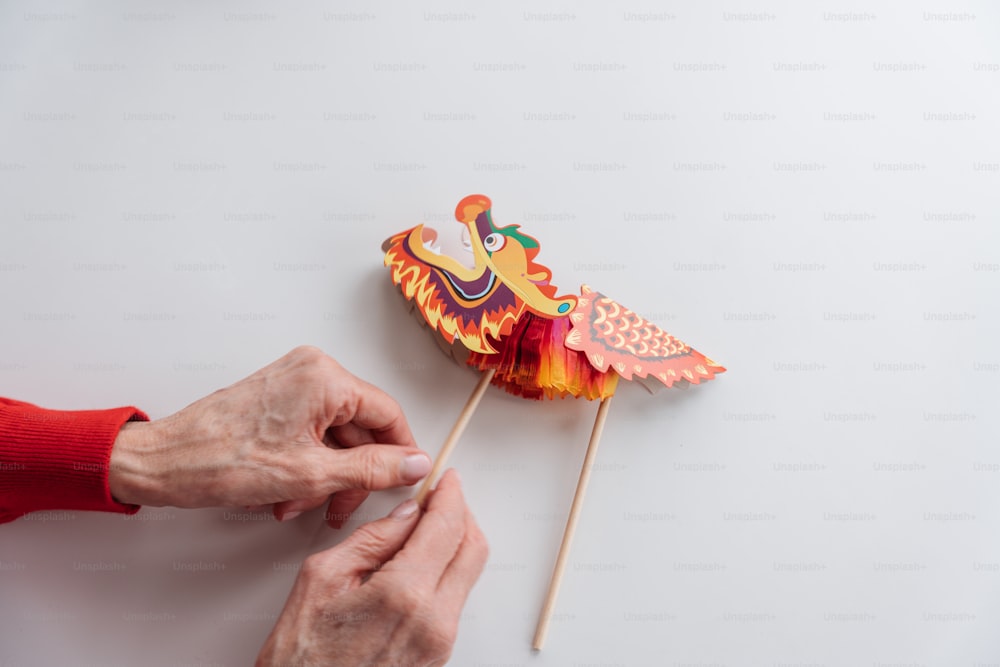 a person is making a paper bird on a stick