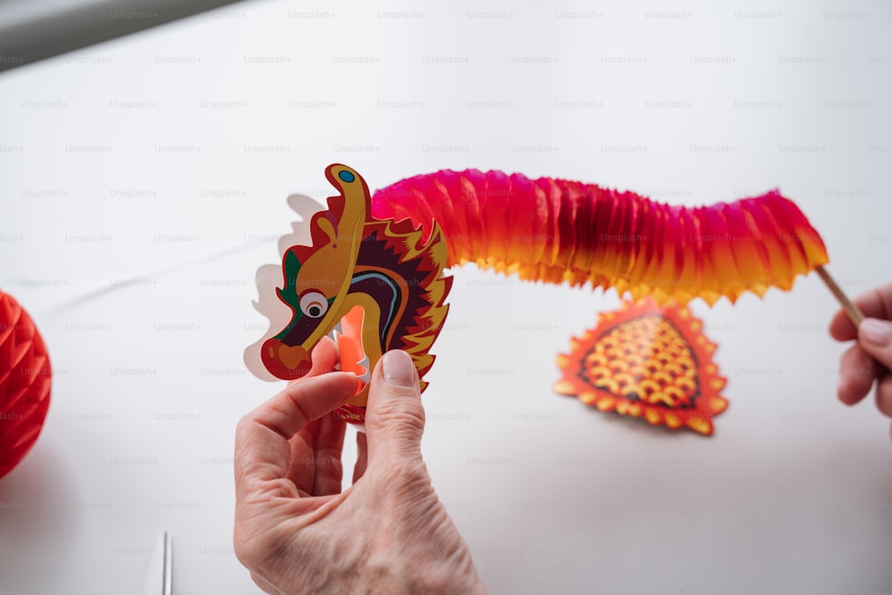 uma pessoa segurando uma decoração de papel em forma de dragão