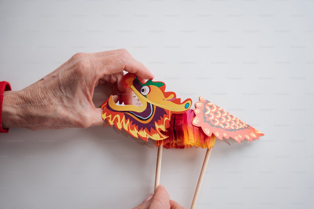 a person holding a dragon shaped toothpick on a stick