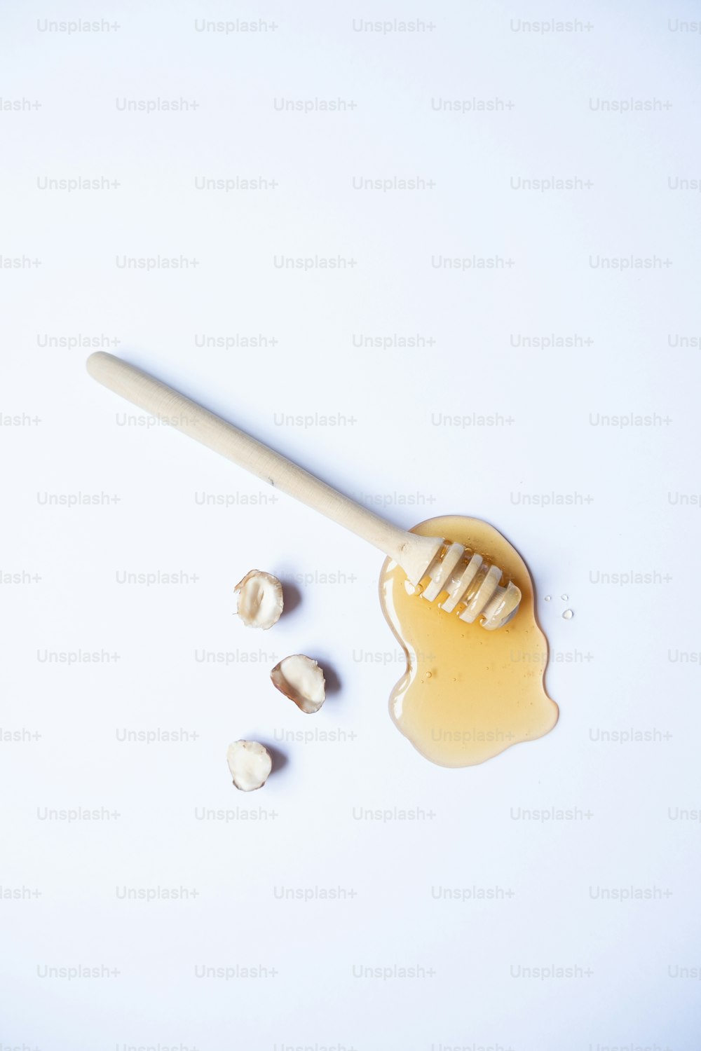 a wooden spoon with honey on it next to some nuts
