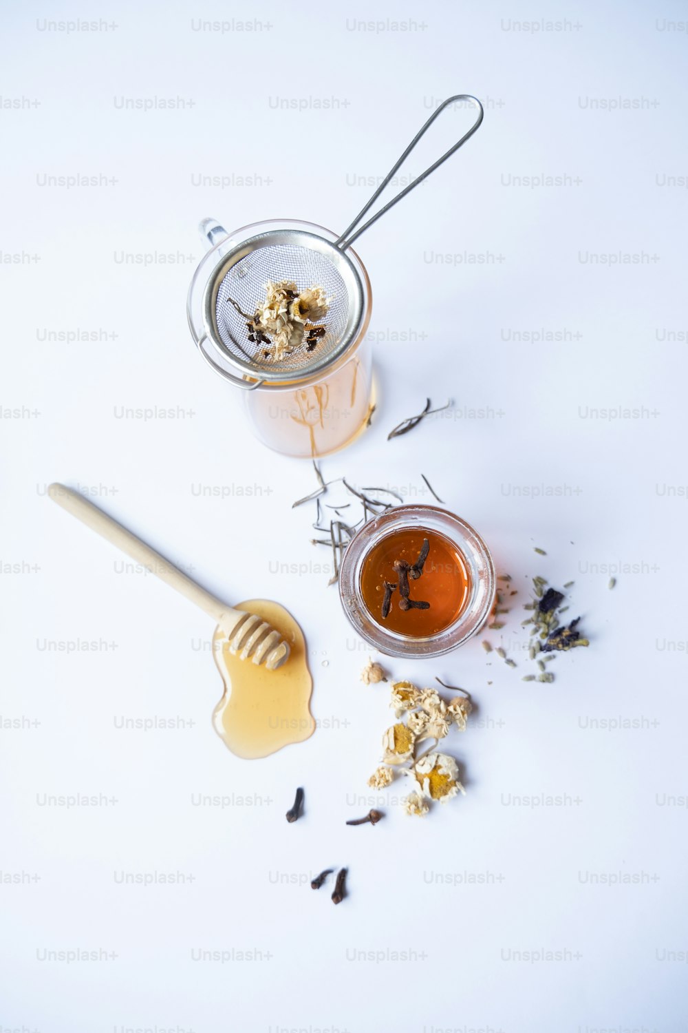 un barattolo di miele e un cucchiaio di miele su una superficie bianca