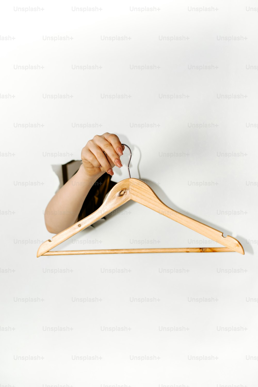 a person holding a pair of scissors in front of a wooden hanger