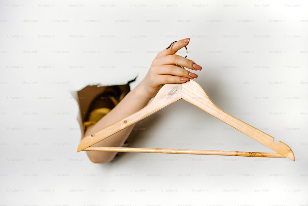 a woman's hand holding a wooden hanger